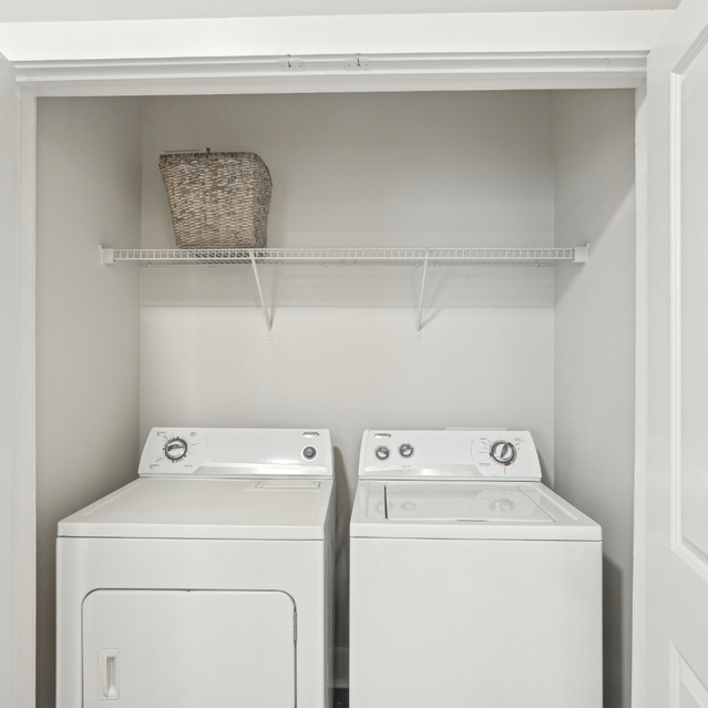 Porter Westside - Apartments in Atlanta, GA - Laundry room featuring a washer and dryer with shelves for cleaning supplies